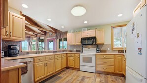 A kitchen with wooden cabinets, a microwave, an oven, and a refrigerator. - Large Home on 1 Acre: 2 Mi to Grand Lake Village (Grand Lake)