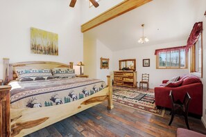 A bedroom with a wooden bed, a red sofa, a wooden dresser, and a window with curtains. - Large Home on 1 Acre: 2 Mi to Grand Lake Village (Grand Lake)