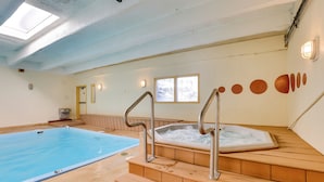 An indoor swimming pool with a 8ft depth marker, wooden steps leading to a hot tub, and a skylight above. - 1 Mi to Dillon Reservoir: Condo Retreat in Frisco! (Frisco)