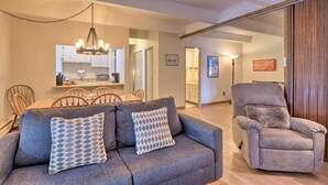 A modern living room with a grey sofa, a recliner, and a dining area with wooden chairs and a chandelier. - 1 Mi to Dillon Reservoir: Condo Retreat in Frisco! (Frisco)