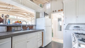 Una cocina con gabinetes blancos, un refrigerador, un fregadero y una estufa.