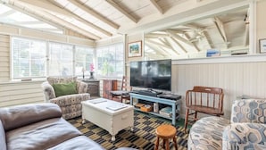 Una sala de estar acogedora con un sofá, sillas, televisor y chimenea.