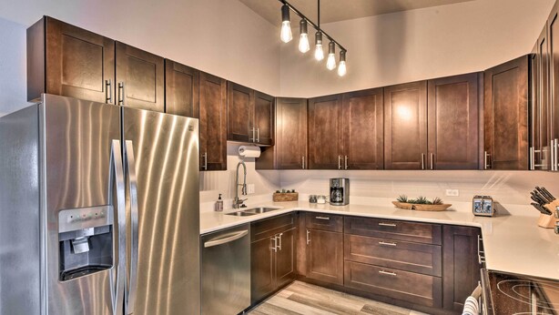 A modern kitchen with stainless steel appliances, dark wooden cabinets, a built-in water dispenser, and a light fixture above the countertop. - Buena Vista Condo: 1/2 Mile to River & Main St! (Buena Vista)