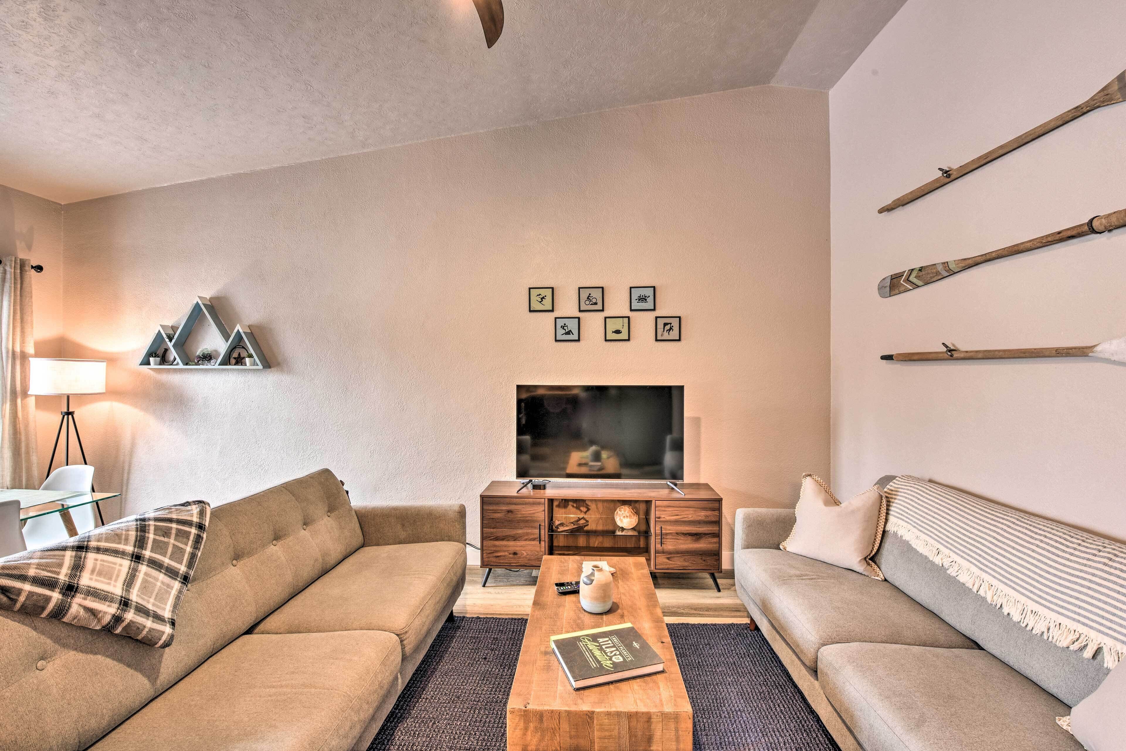 Ein modernes Wohnzimmer mit einer Couch, einem Couchtisch, einem Fernseher und Wanddekoration.