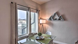 A modern dining area with a glass table, white chairs, and a view of the outside through large windows. - Buena Vista Condo: 1/2 Mile to River & Main St! (Buena Vista)