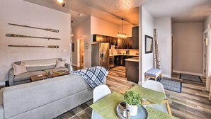 A modern living room with a sofa, coffee table, and a dining area with a table and chairs. There is a kitchen in the background with a refrigerator, stove, and cabinets. - Buena Vista Condo: 1/2 Mile to River & Main St! (Buena Vista)