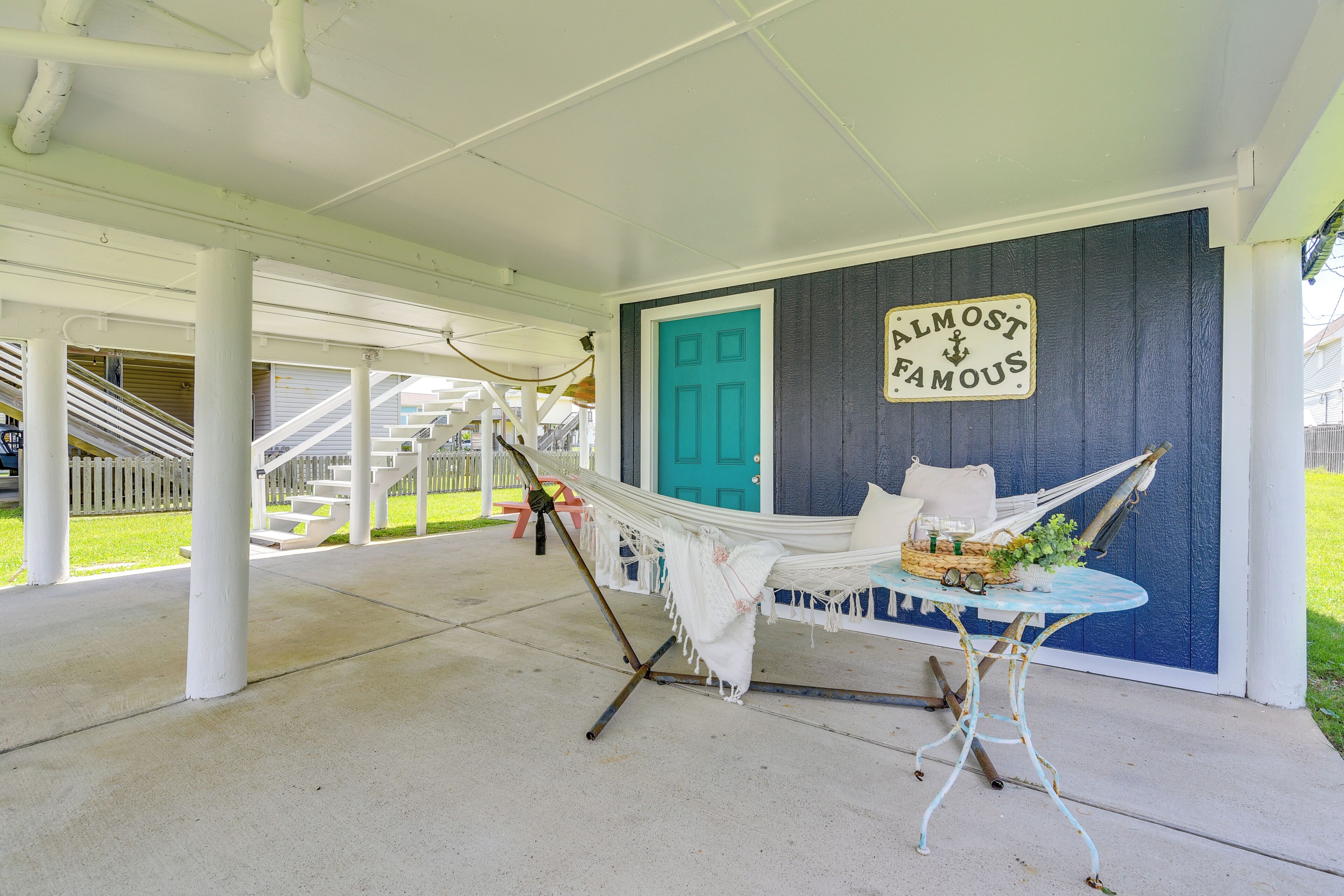A porch with a hammock, a table with a basket, and a sign that says "ALMOST FAMOUS".