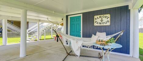 A porch with a hammock, a table with a basket, and a sign that says "ALMOST FAMOUS".