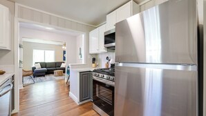 A modern kitchen with stainless steel appliances, wooden flooring, and a grey cabinet. - Fayetteville Retreat w/ Yard - Walk to Campus! (Fayetteville)