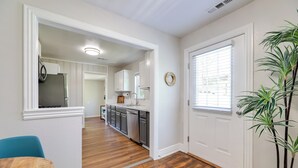 A kitchen with white cabinets, a refrigerator, and a sink. There is a dining table with chairs and a potted plant. - Fayetteville Retreat w/ Yard - Walk to Campus! (Fayetteville)