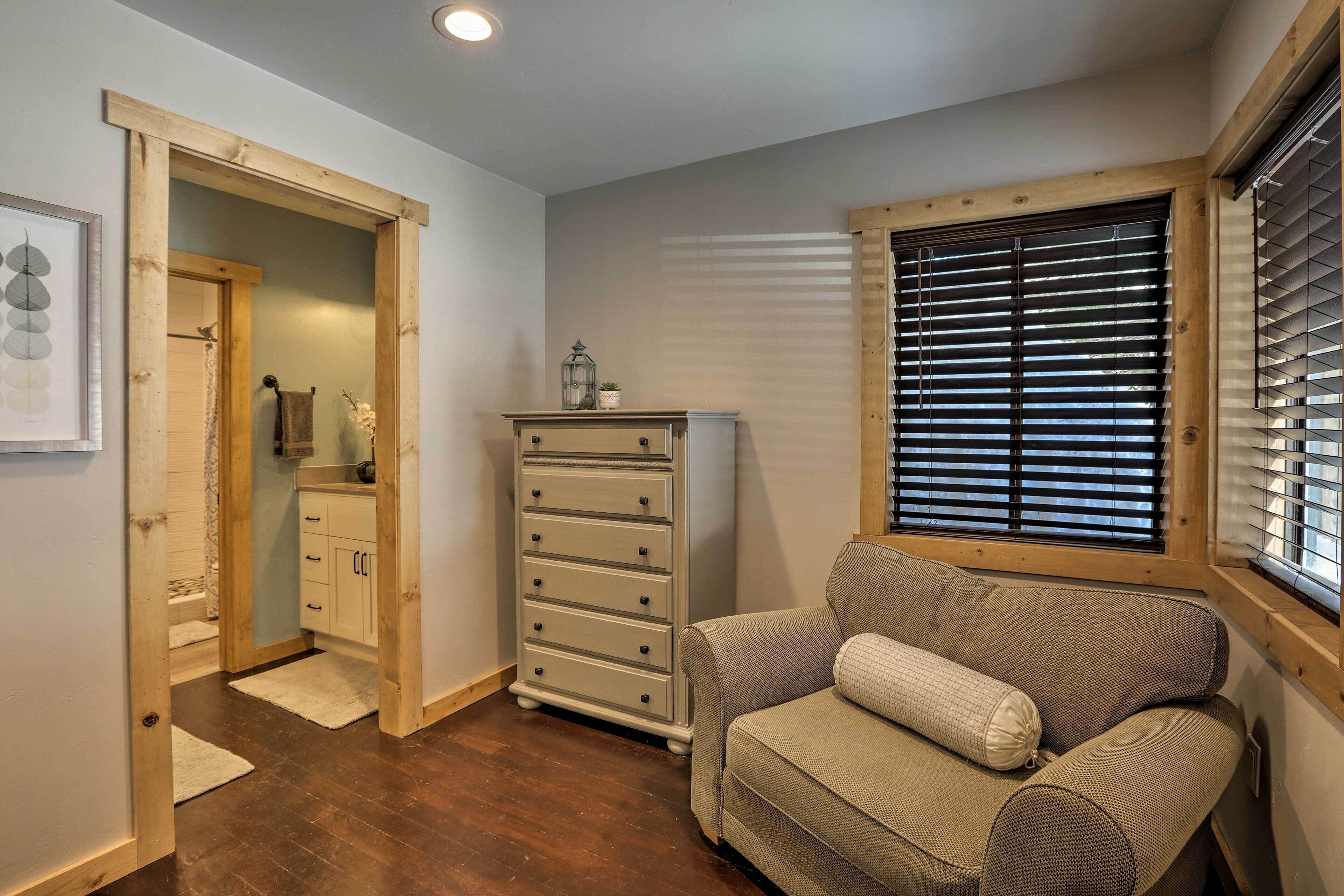 Um quarto aconchegante com uma cômoda de madeira, um banco acolchoado e uma janela com persianas.
