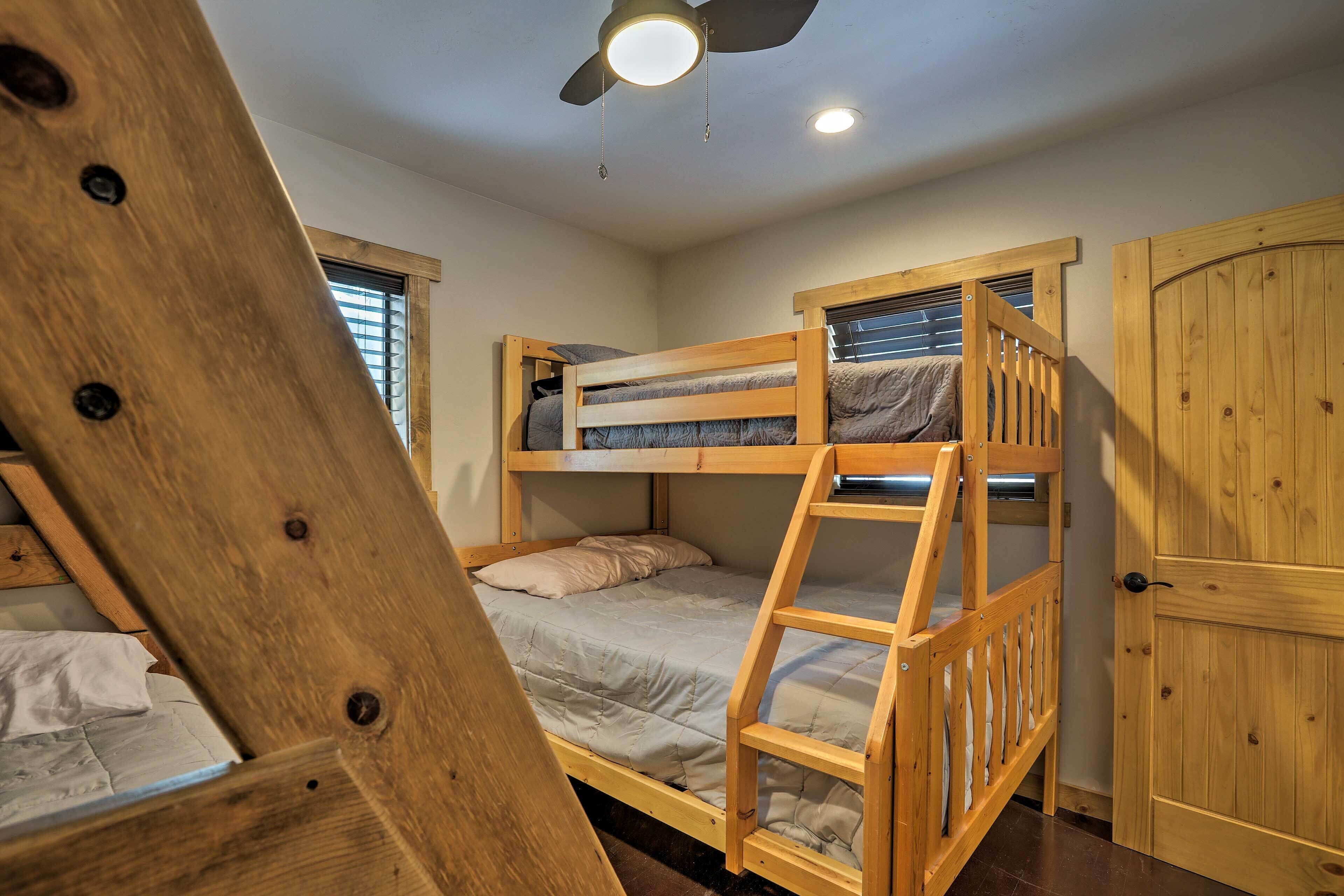 A bunk bed room with a wooden ladder, a ceiling fan, and a wooden door.