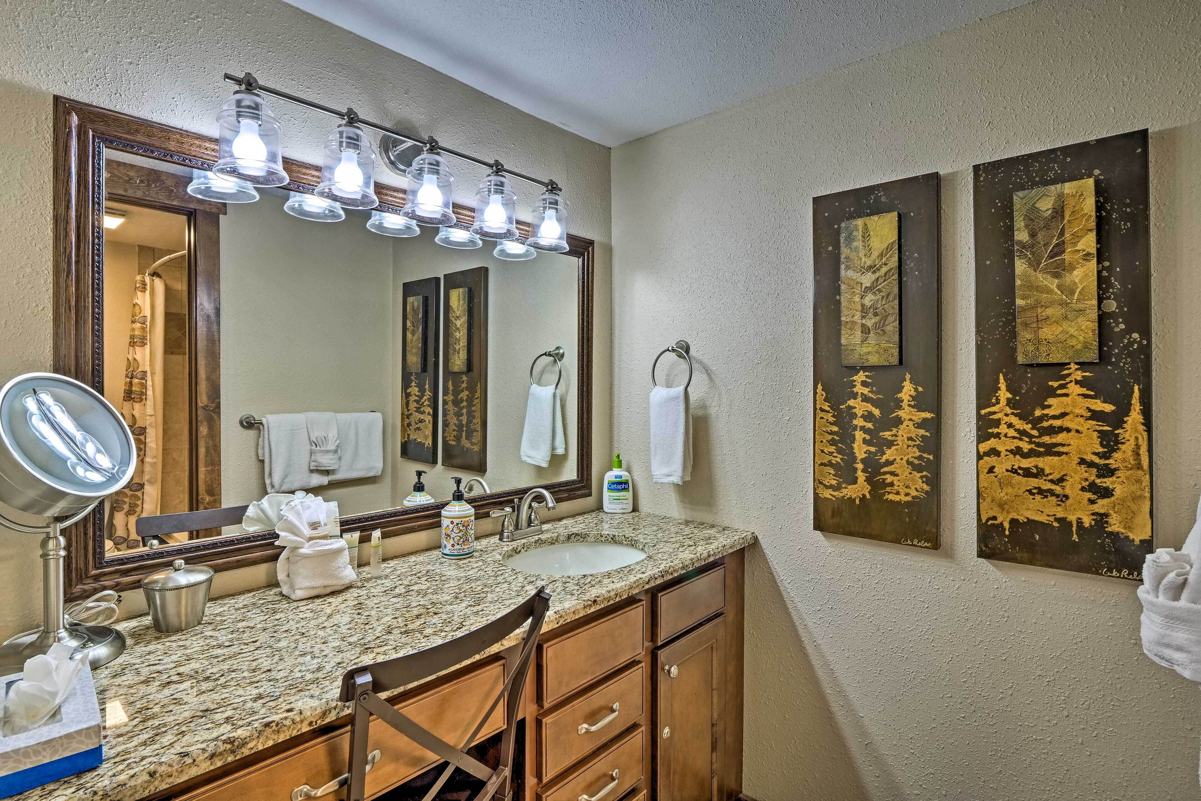 A bathroom with a granite countertop, a large mirror, a sink, and a vanity with wooden cabinets.