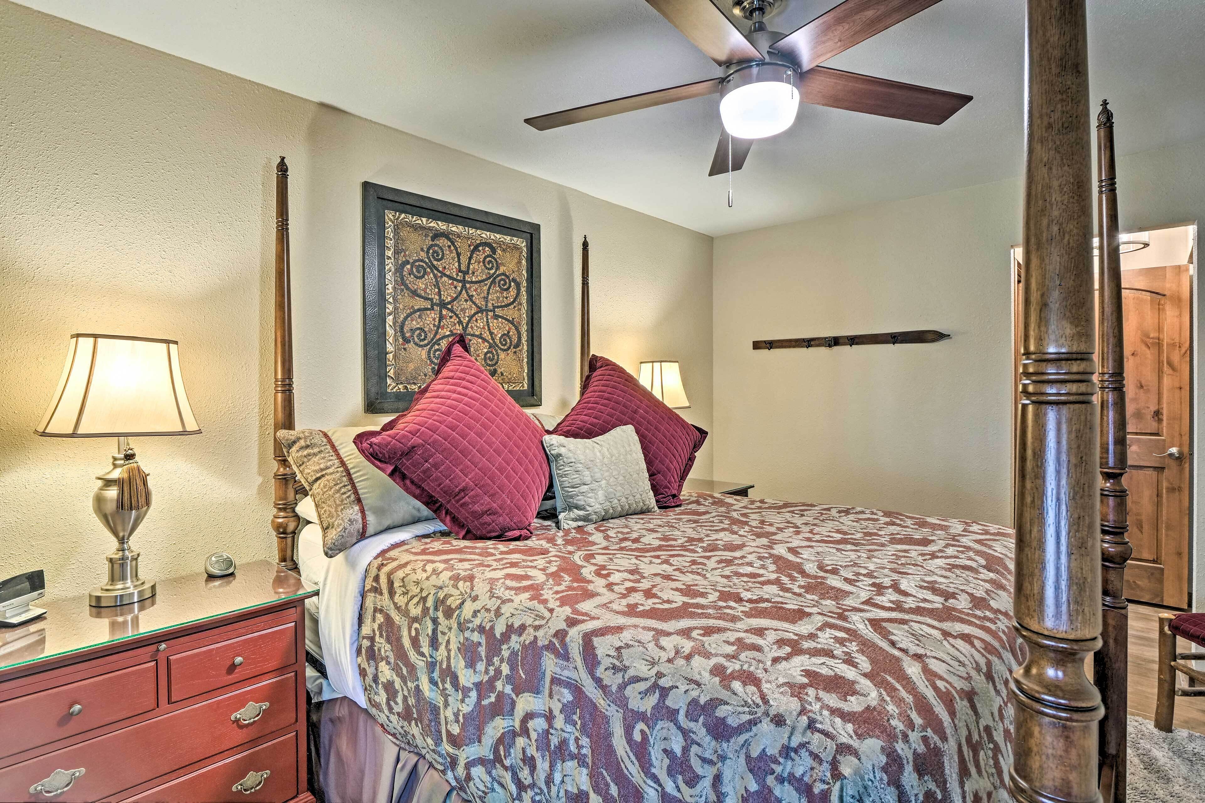 A bedroom with a bed, a nightstand, a lamp, a ceiling fan, and a wooden chair.