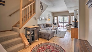 A spacious living area with a staircase, a sofa set, a coffee table, and a TV. - Pet-friendly Fraser Condo w/ Community Hot Tub (Fraser)
