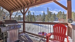 A covered outdoor area with a grill, a red chair, and a view of a snowy landscape and trees. - Pet-friendly Fraser Condo w/ Community Hot Tub (Fraser)