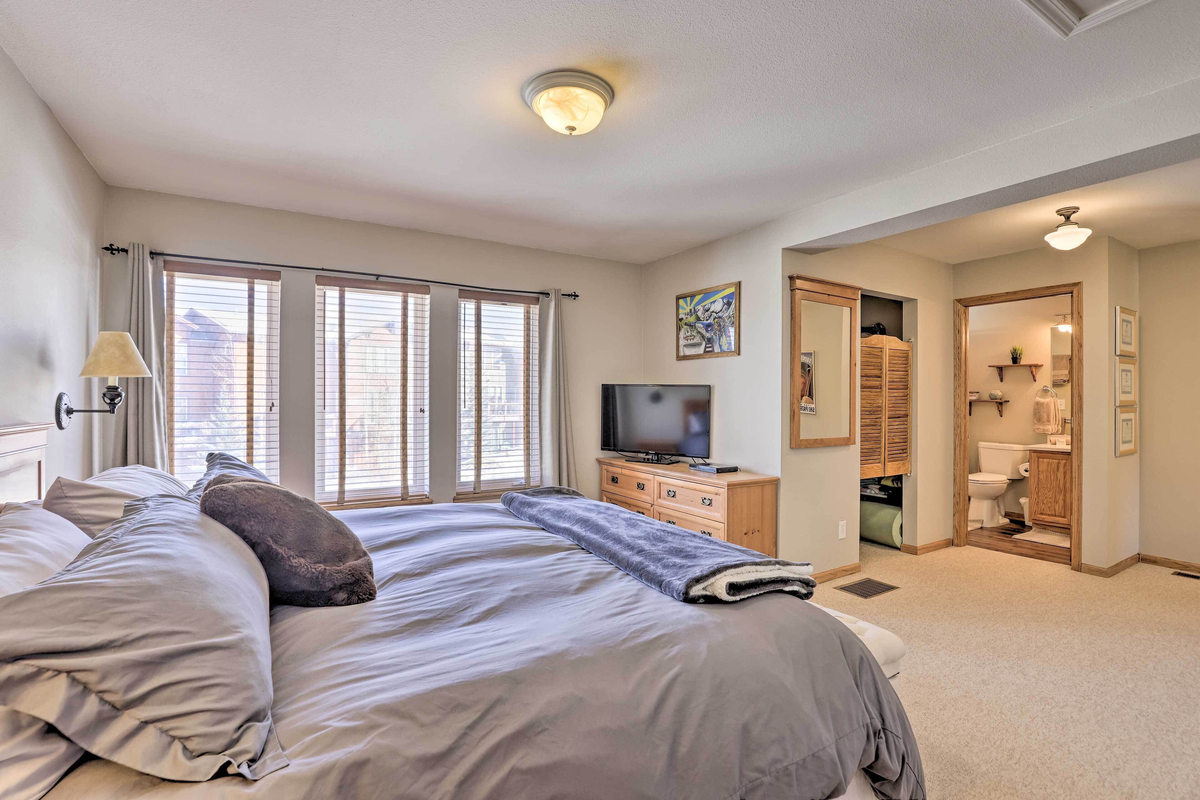 A bedroom with a large bed, a TV, and a bathroom visible through an open door.