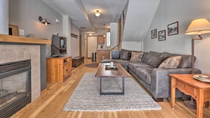 A modern living room with a fireplace, a sofa, a coffee table, and a TV. - Pet-friendly Fraser Condo w/ Community Hot Tub (Fraser)