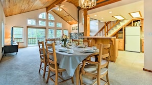 A spacious dining area with a high ceiling and wooden beams, a staircase leading to a second floor, and a kitchen area with a refrigerator and cabinets. - Hot Tub Access, Near Skiing: Tahoe Donner Cabin (Truckee)