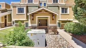 A multi-story residential building with a stone foundation, a central entrance with a door, and a small porch area. - Ski Getaway! Mtn-view Condo Near Keystone Resort (Dillon)