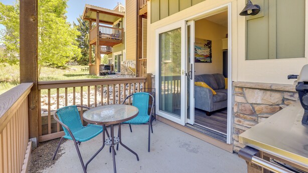 An outdoor patio with a table and chairs, a barbecue grill, and a sliding glass door leading to a living area with a couch and a painting. - Ski Getaway! Mtn-view Condo Near Keystone Resort (Dillon)