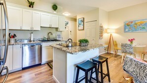 A modern kitchen with white cabinets, a stainless steel dishwasher, granite countertops, and a central island with bar stools. - Ski Getaway! Mtn-view Condo Near Keystone Resort (Dillon)