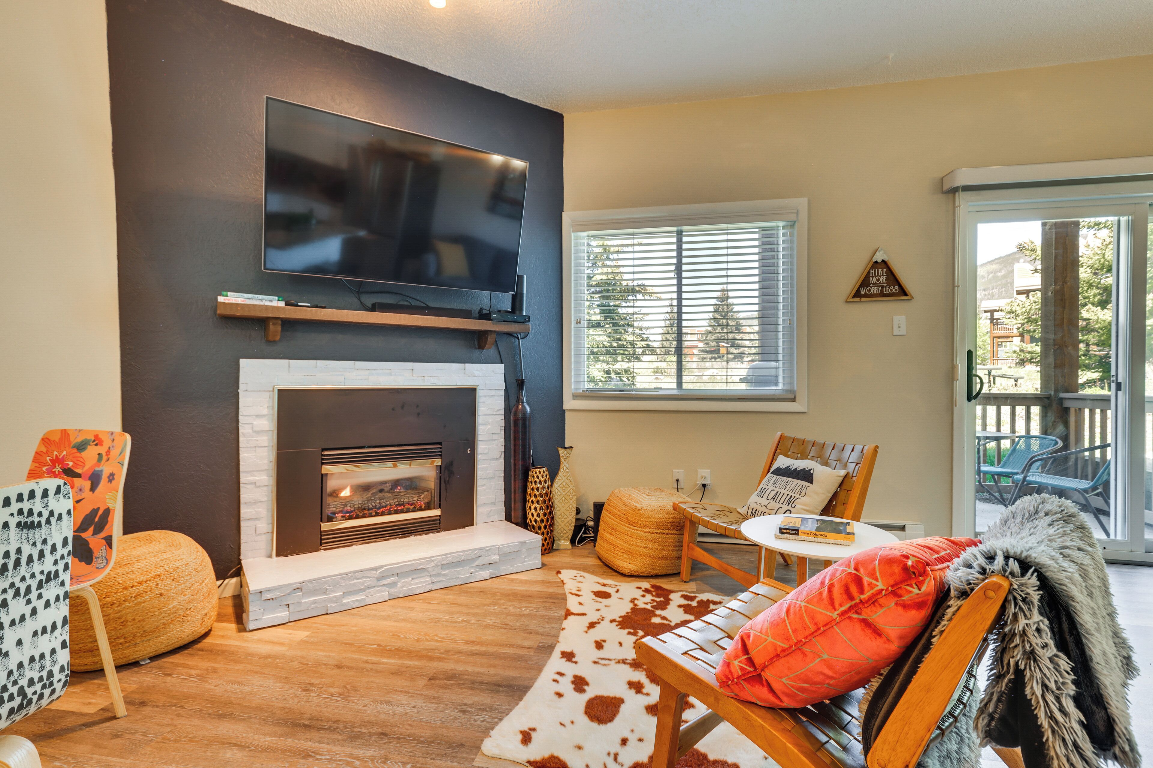 A living room with a fireplace, a flat-screen TV mounted above it, and a comfortable seating area with a sofa and chairs.