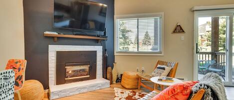 A living room with a fireplace, a flat-screen TV mounted above it, and a comfortable seating area with a sofa and chairs.