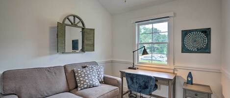 A room with a sofa, desk, chair, and a small table.