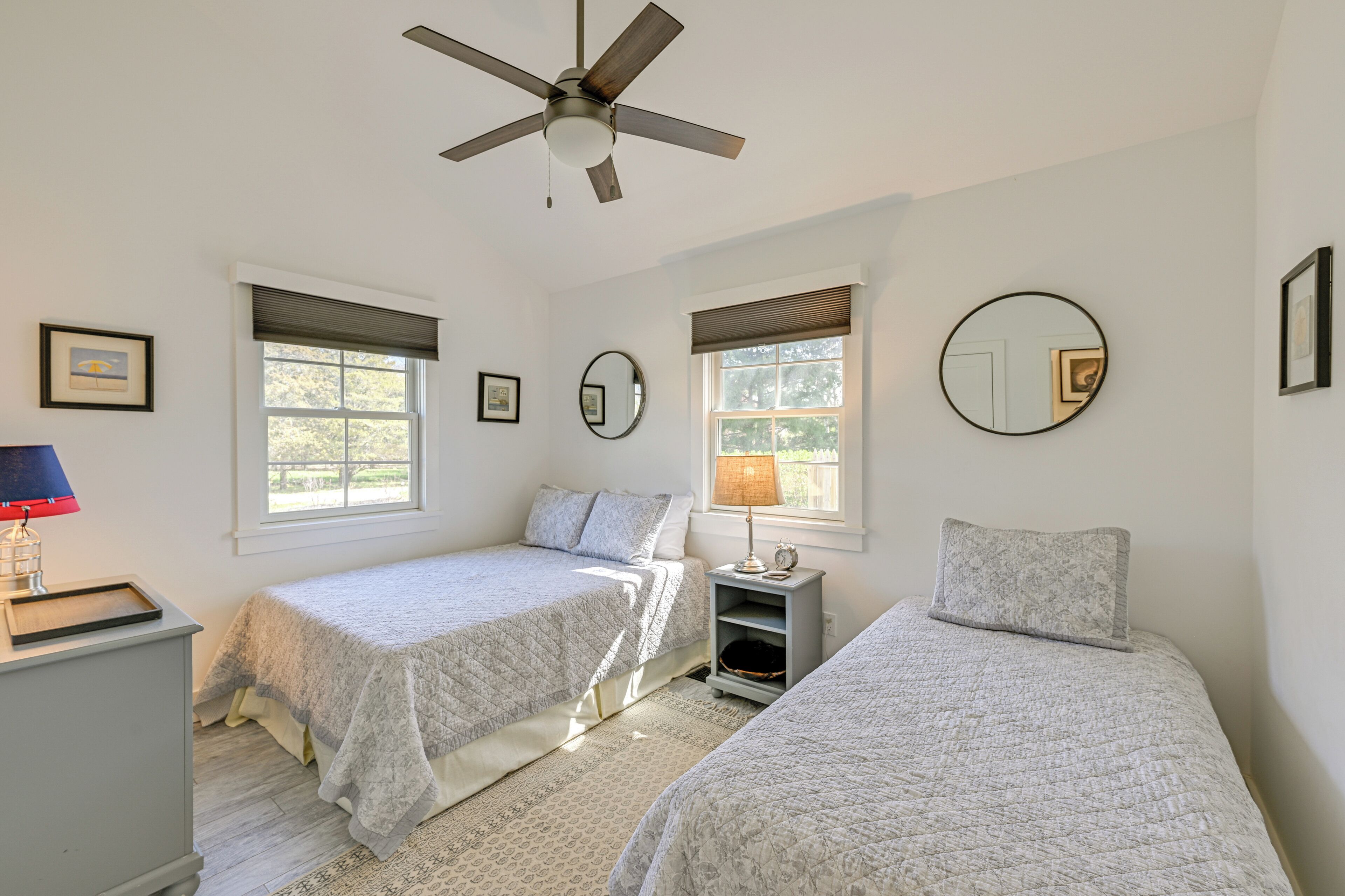 A bedroom with two beds, a ceiling fan, and a window with blinds.