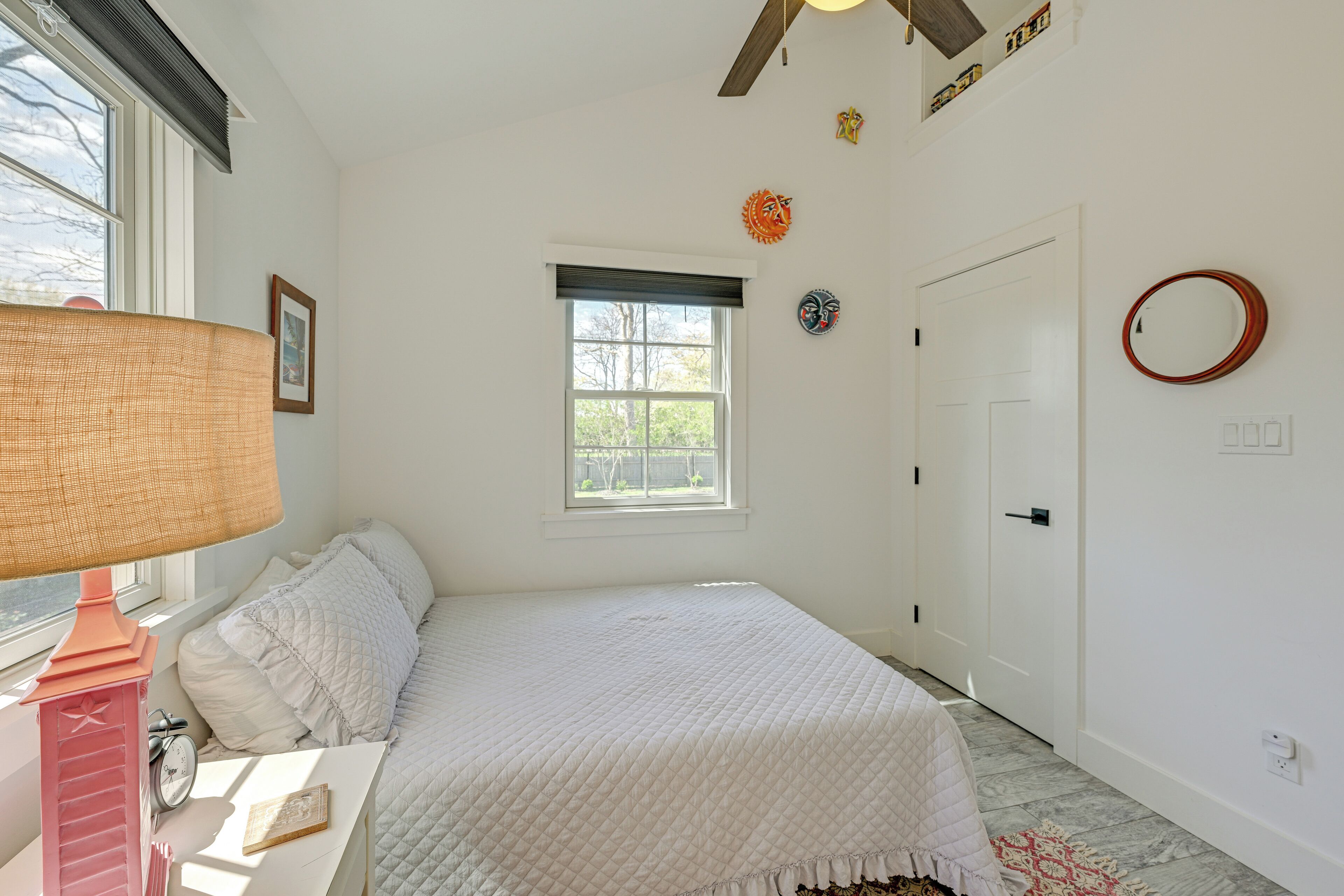 Une chambre à coucher avec un lit, une fenêtre, une porte et une horloge murale.
