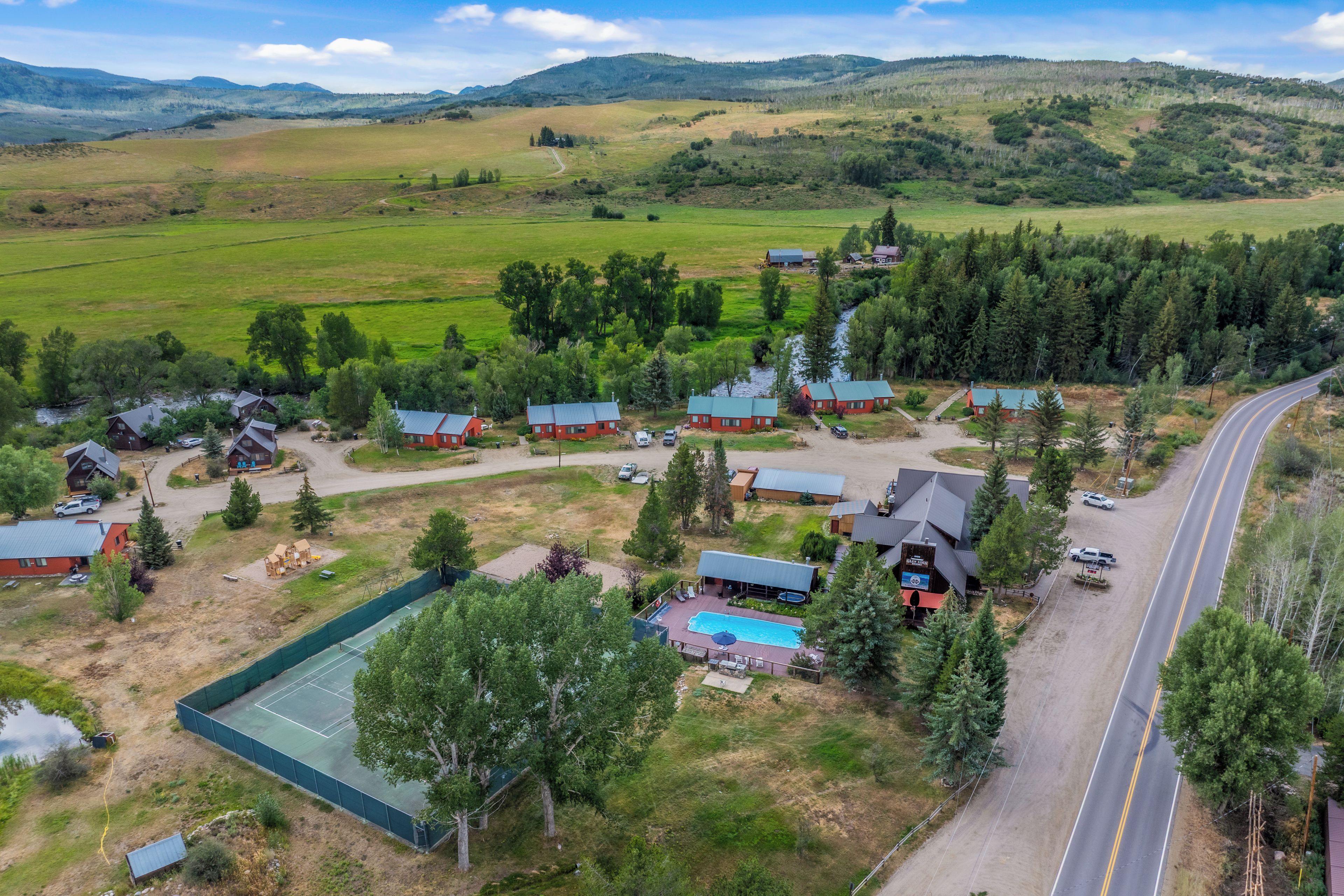 A rural property with multiple cabins, a swimming pool, and a road.
