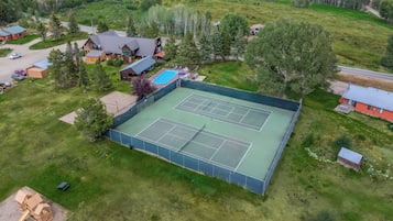 An aerial view of a residential area with a tennis court, houses, and a swimming pool.