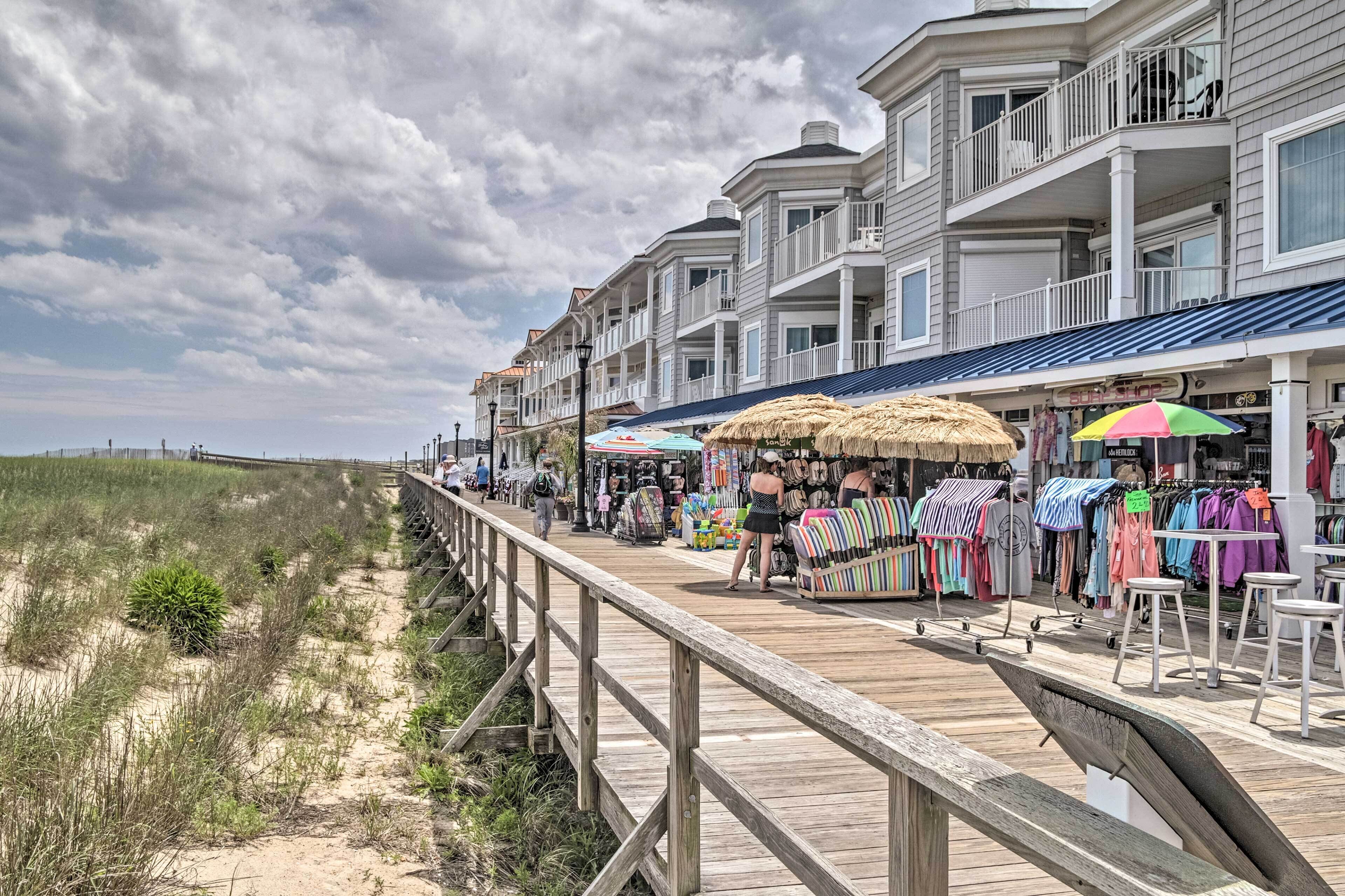 A wooden boardwalk with shops and a beach in the background.