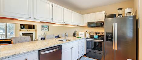 A modern kitchen with white cabinets, a stainless steel refrigerator, a microwave, and a dishwasher.