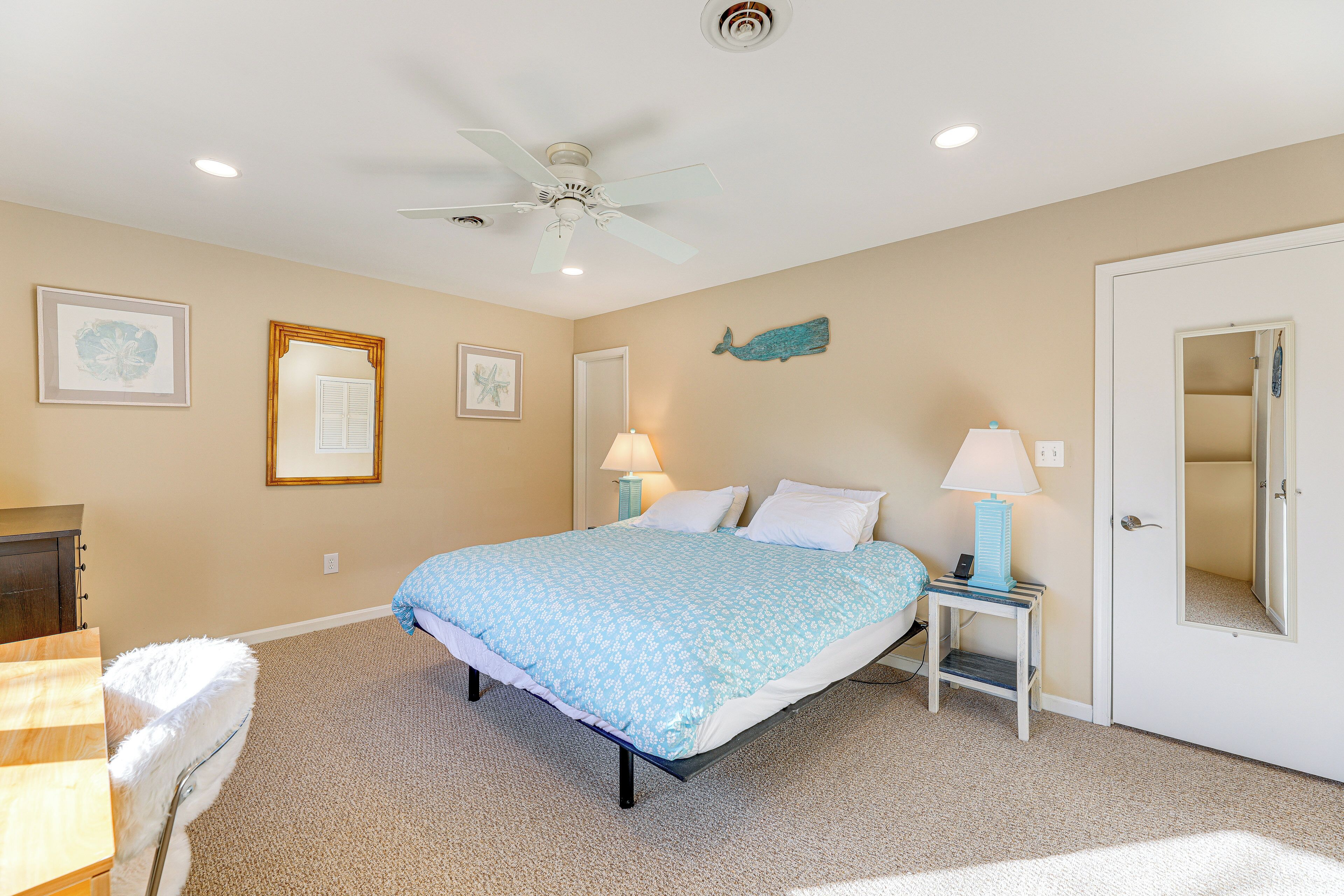A bedroom with a bed, two bedside lamps, a ceiling fan, and a framed picture on the wall.