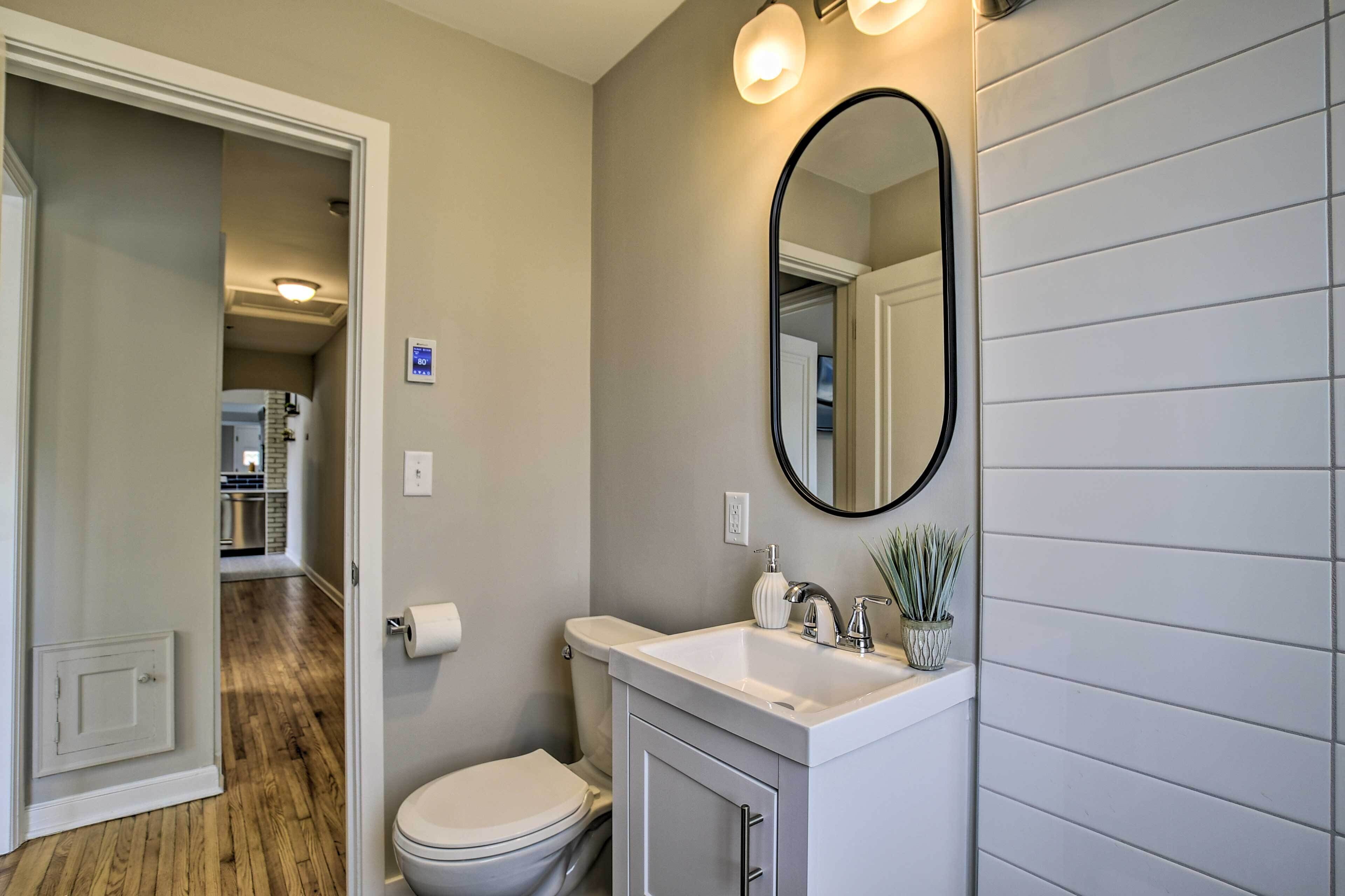 A bathroom with a toilet, sink, and mirror.
