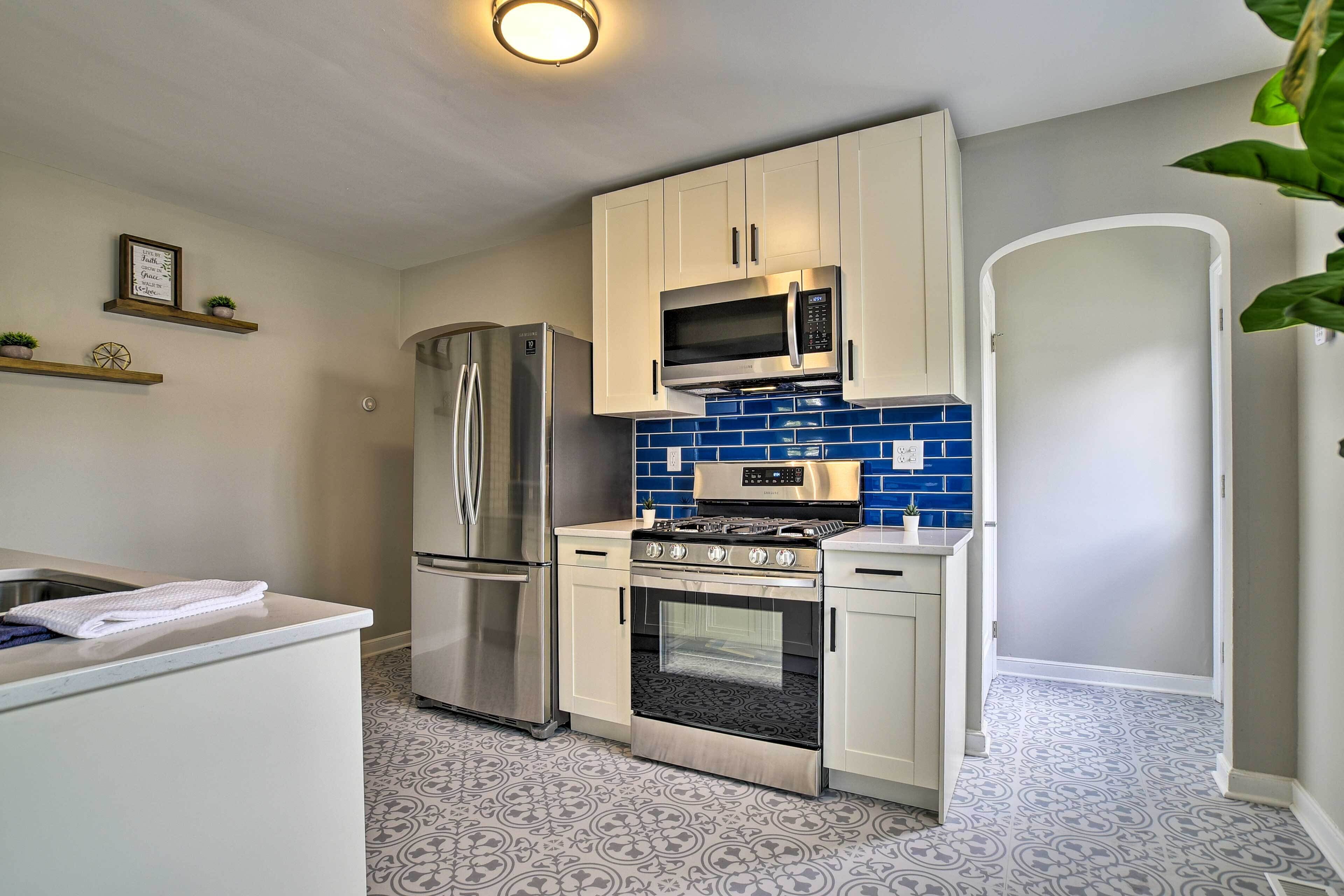 A modern kitchen with stainless steel appliances, white cabinets, and blue backsplash tiles.