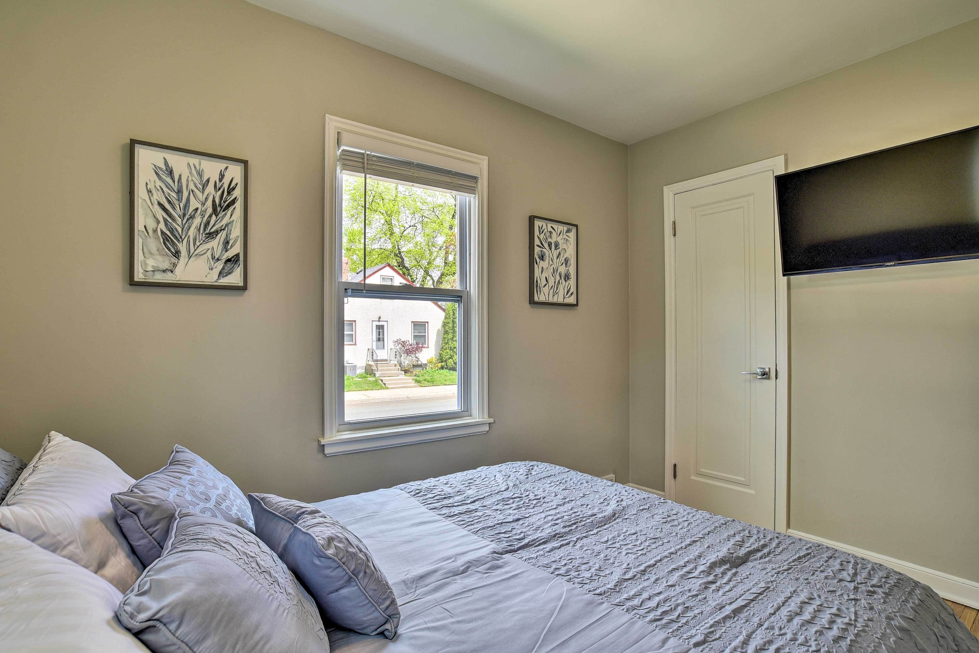 A bedroom with a bed, a window, and two framed artworks on the wall.