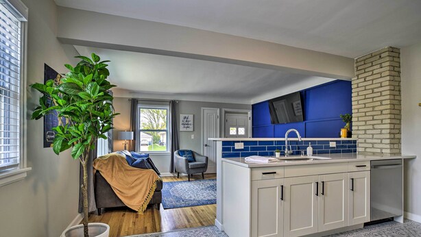 A modern kitchen with white cabinets, a blue backsplash, and a brick chimney. - Mpls Duplex w/ Wifi & Kitchen: 5 Mi to Dtwn! (Minneapolis)