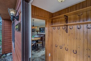 Een houten buitenmuur met een deur, een hangende lamp en een rij hertenhoeken.