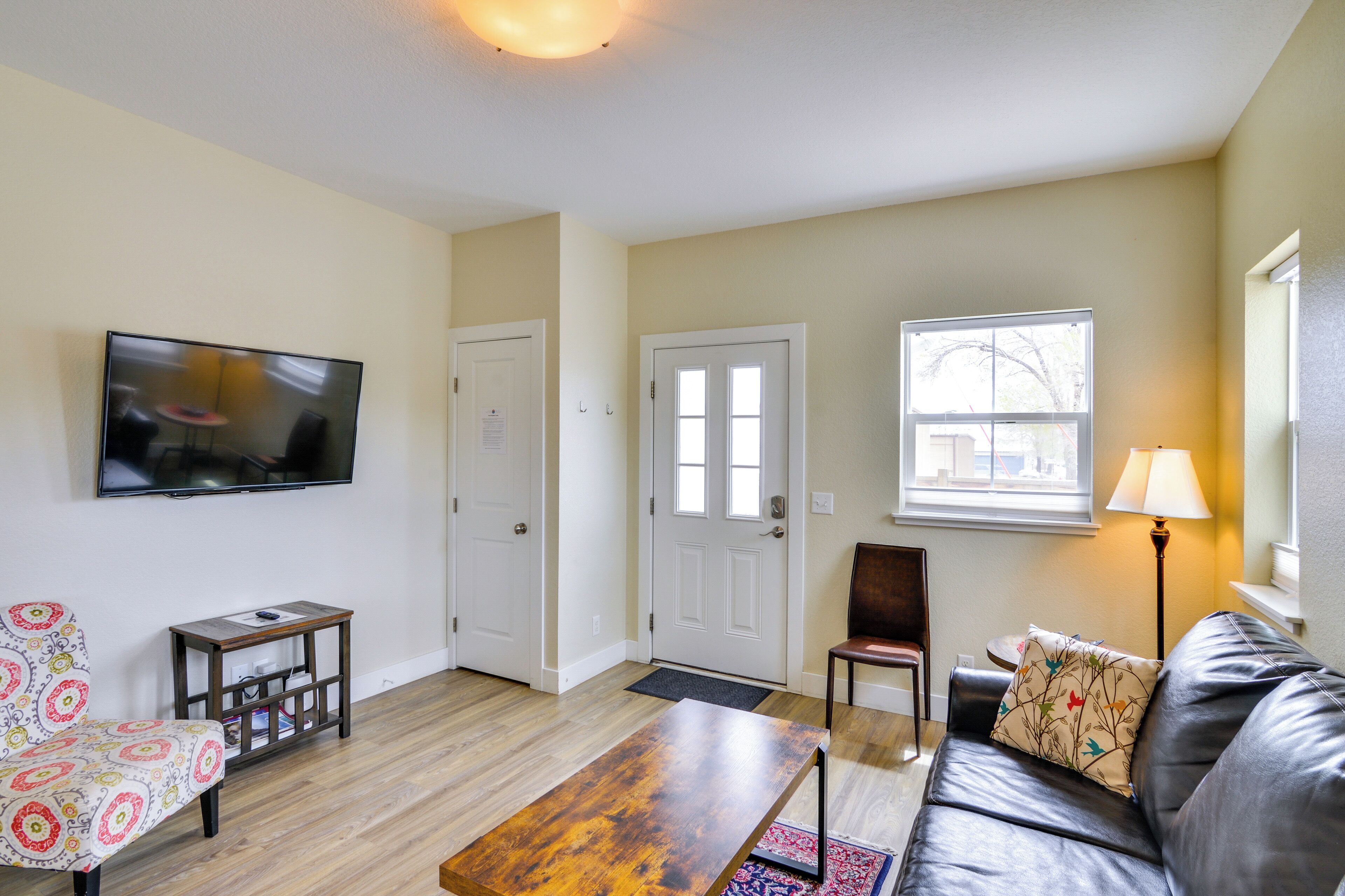 A living room with a flat-screen TV, a sofa, a coffee table, a patterned armchair, and a lamp.
