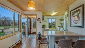 A modern kitchen with a large island, wooden flooring, and large windows.