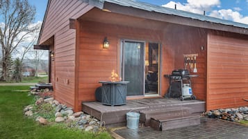 Enjoy a peaceful retreat in this cabin, featuring a spacious interior, outdoor seating area, and grill, surrounded by a beautifully landscaped garden.