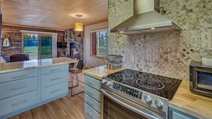 A modern kitchen with a large island, built-in oven, and a microwave.