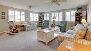 A spacious living room with a high ceiling, large windows, and a ceiling fan. - Westerly Retreat ~ 1/4 Mi to Private Beach! (Westerly)