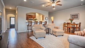 A spacious living room with a high ceiling fan, hardwood flooring, and a neutral color palette.
