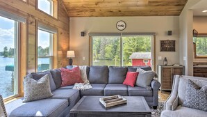 A cozy living room with a large sectional sofa, a coffee table, and a view of a lake. - Spacious Lakeside Family Home on Big Bearskin Lake (Harshaw)