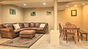 A living room with a brown leather sectional sofa, a matching ottoman, and a dining area with wooden chairs and a table. - CO Springs Apartment < 6 Mi to Garden of the Gods! (Colorado Springs)