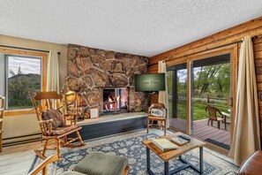A cozy living room with a stone fireplace, comfortable seating, and a television.